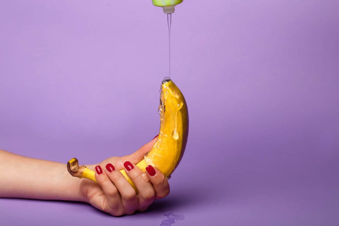 A hand holding a banana with liquid dripping from above  